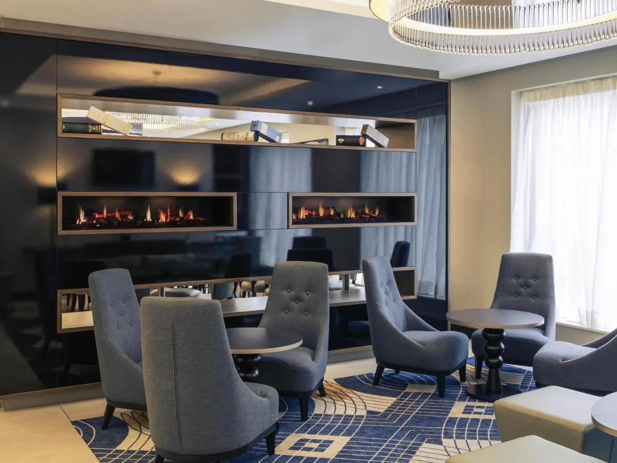 a room with a fireplace with chairs and a table at Mercure Edinburgh Haymarket in Edinburgh