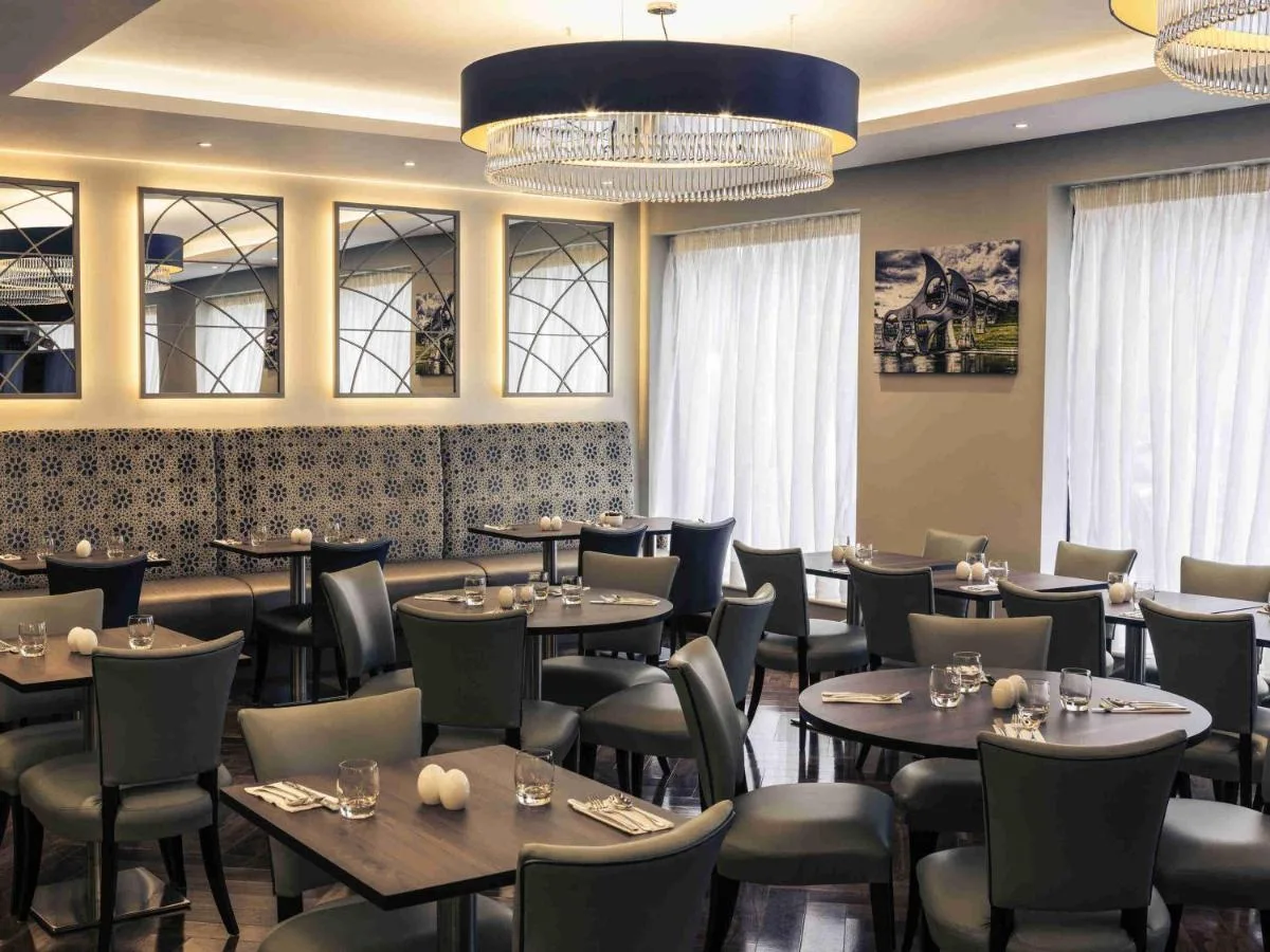 a dining room with tables and chairs and a chandelier at Mercure Edinburgh Haymarket in Edinburgh